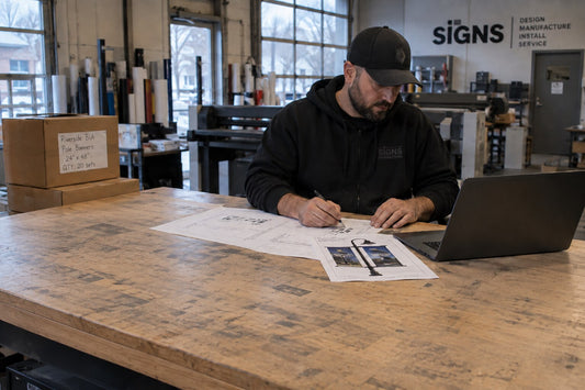 Canadian sign company project manager reviewing pole banner hardware specifications and project drawings.